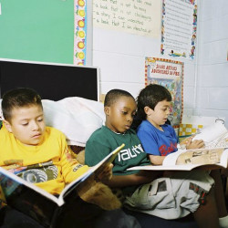 A picture of 3 boys reading magazines.