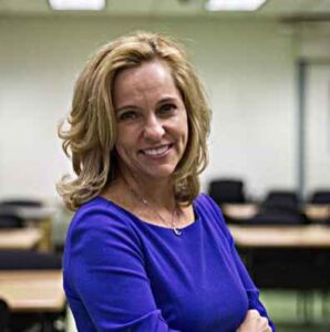 A woman in a classroom wearing a blue shirt.