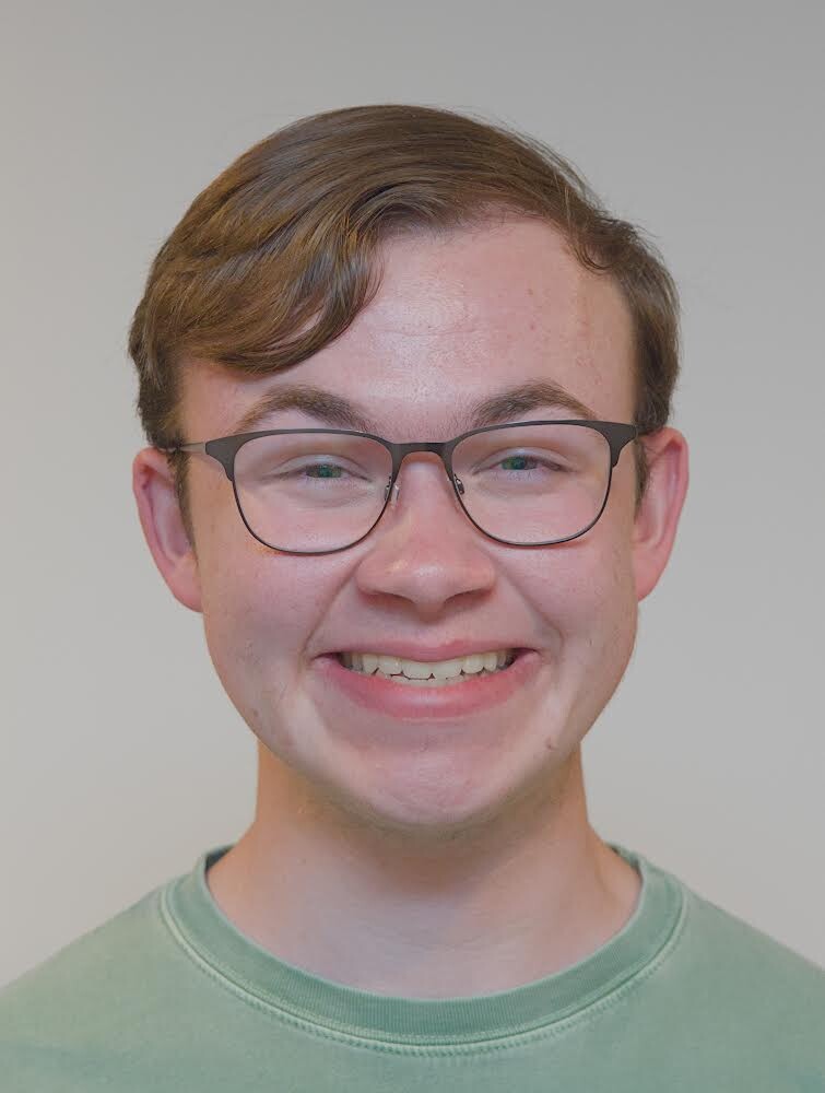 A man with glasses on smiling in a green shirt.